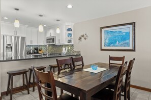 A modern kitchen with white cabinets, a stainless steel refrigerator, and a tiled backsplash.