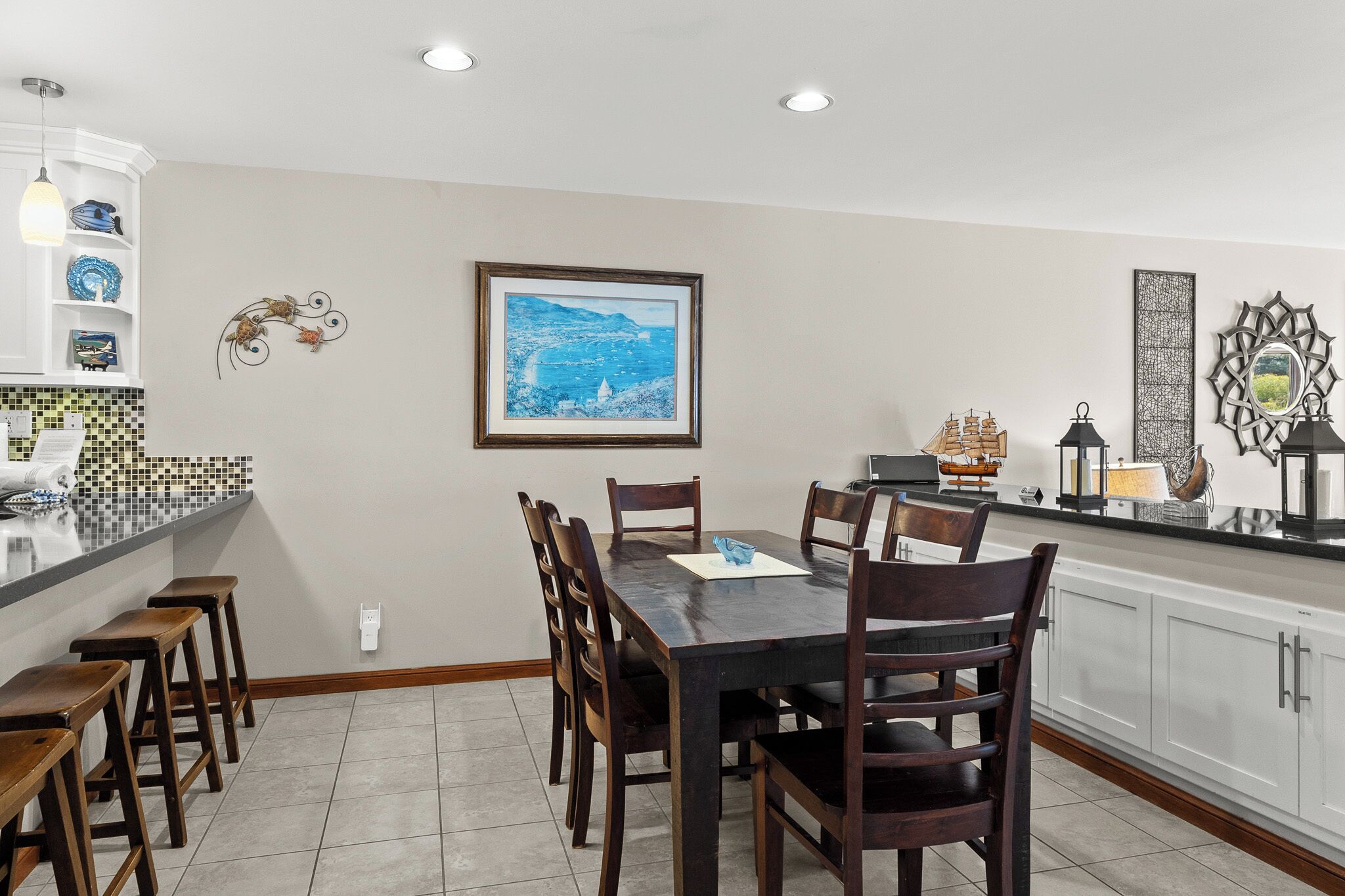 A kitchen with a dining table, bar stools, and a tiled backsplash.