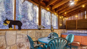 A wooden cabin with stone walls, a stone table with chairs, a hot tub, and a bear decoration on the windowsill. - ER317 - The Cubby Hole - Great location - Close to town (Pigeon Forge)