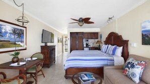 Une chambre d’hôtel comprenant un lit, un canapé, un coin repas avec des chaises, une télévision, un ventilateur de plafond et un coin cuisine.