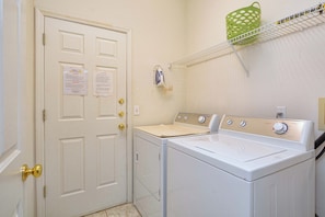 A laundry room with a white door, a washing machine, and a dryer. - 3BR Disney-Area Pool Home | 2 King Beds | BBQ Grill | Dog Friendly (Davenport)