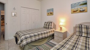 Un dormitorio con dos camas, una mesita de noche, una lámpara y una puerta.