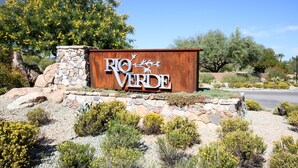 A sign for Rio Verde with a stone wall and desert landscaping. - Rio Verde Townhouse overlooking the golf course. (Rio Verde)