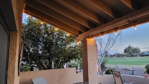 A covered outdoor area with string lights, a view of a golf course, and a patio with a table and chairs. - Rio Verde Townhouse overlooking the golf course. (Rio Verde)