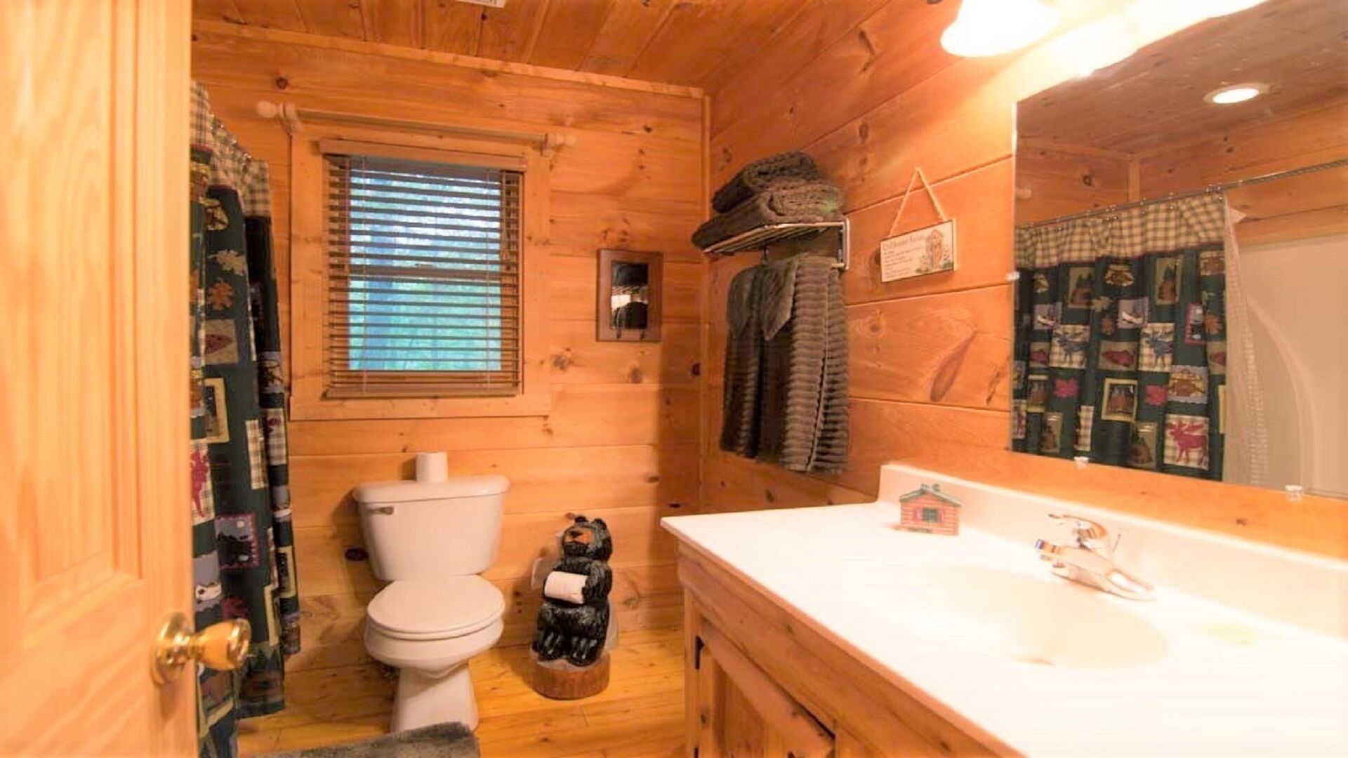 A wooden cabin bathroom with a toilet, sink, and a mirror.