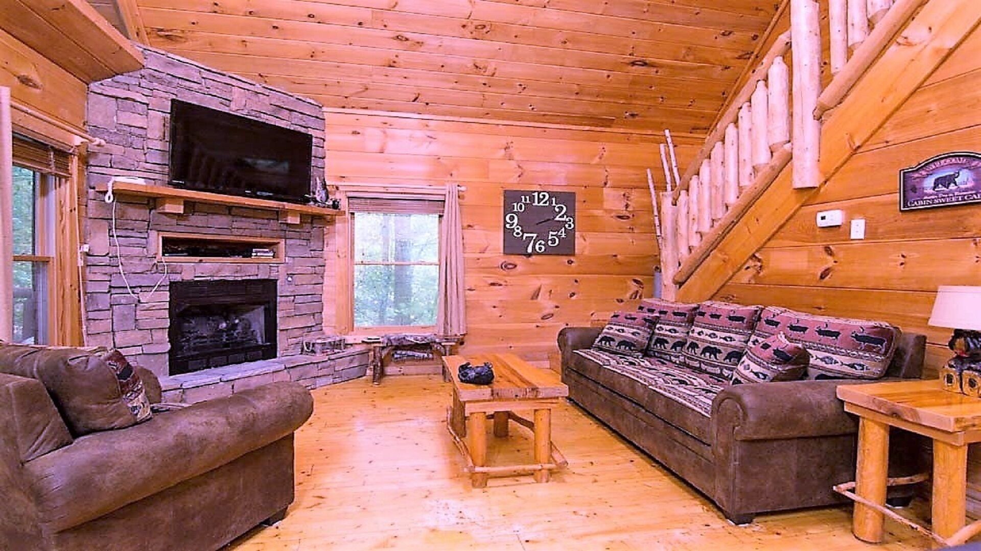Ein gemütliches Blockhaus-Interieur mit Kamin aus Stein, Holzwänden, einer Couch und einer Uhr.