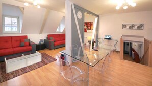 A modern living room with a glass dining table, red sofas, and a fireplace. - gluck duplex 97m2 city center 3br 2bth (Colmar)