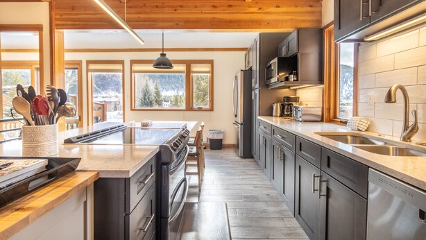 A modern kitchen with wooden beams, stainless steel appliances, and large windows offering a view of the outdoors. - Keystone Townhome Close to Shuttle for Lifts & Short Walk to Lakeside Village (Keystone)