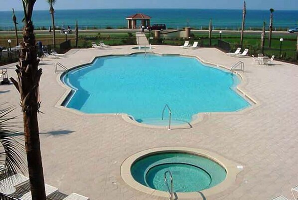 A large, irregularly shaped swimming pool with a smaller circular hot tub in the center, surrounded by lounge chairs and palm trees. - Mediterranea 210D-Steps to the private beach (Destin)