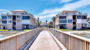 Un paseo marítimo que conduce a un edificio moderno con varios balcones y una zona cubierta.