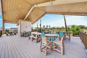 An outdoor deck with wooden furniture and a covered area. - This spacious 2/2 is located right in the heart of Port A! Private fishing pier! (Port Aransas)