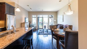 A modern kitchen with granite countertops, stainless steel appliances, and a dining area with a dark wood table and chairs. - Barona Beach Lakefront Condo (West Kelowna)