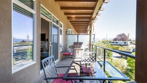 A balcony with a glass table, chairs, and a grill. - Barona Beach Lakefront Condo (West Kelowna)