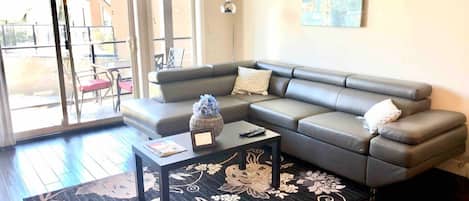 A living room with a grey sectional sofa, a black coffee table, and a floral rug.