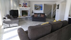 Ein Wohnzimmer mit Kamin, einer Couch, einem Fernseher und einem Bild an der Wand.