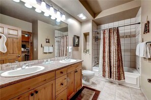 A bathroom with two sinks, a shower, and a toilet.