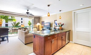 A modern kitchen with a granite countertop, wooden cabinets, and a built-in TV.