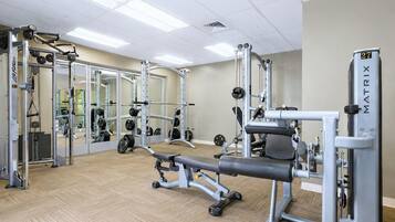 Une salle de sport équipée de matériel de musculation, de miroirs et dotée d’un plancher en bois.