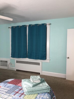 Cozy retreat with a bed, radiator, and window with curtains.