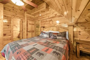 A wooden cabin bedroom with a bed, pillows, and a quilt. - Cherokee Charm: Theater, Gameroom, Hot Tub, Sauna (Gatlinburg)