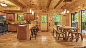A wooden cabin interior with a kitchen, dining area, and bar.