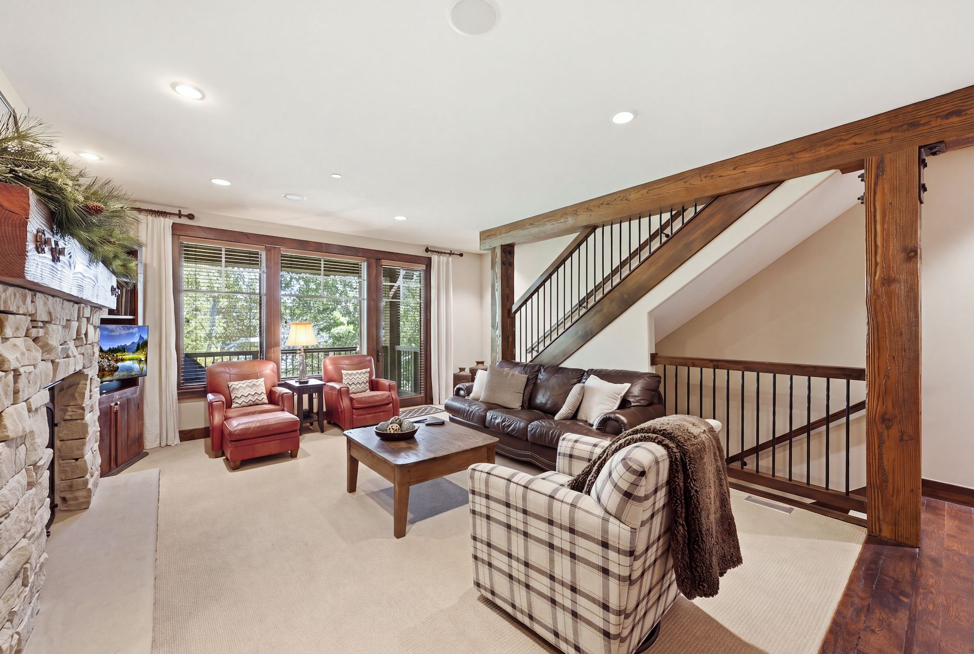 A spacious living room with a fireplace, leather sofas, a coffee table, and a staircase leading to an upper level.