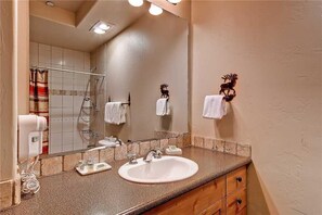 A bathroom with a sink, mirror, towel rack, and shower.