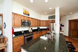 Enjoy cooking in this well-equipped kitchen with a central island, stove, and ample cabinetry.