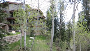 Un immeuble résidentiel doté d’un mur de soutènement en pierre, d’une zone herbeuse et d’un petit ruisseau.