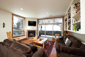 Cozy living room with a fireplace, large window, and comfortable seating area.