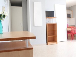 A modern, minimalistic room with a wooden desk, a TV on a stand, and a red chair.