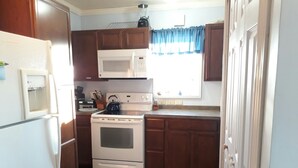 A compact kitchen with a refrigerator, microwave, stove, and oven.