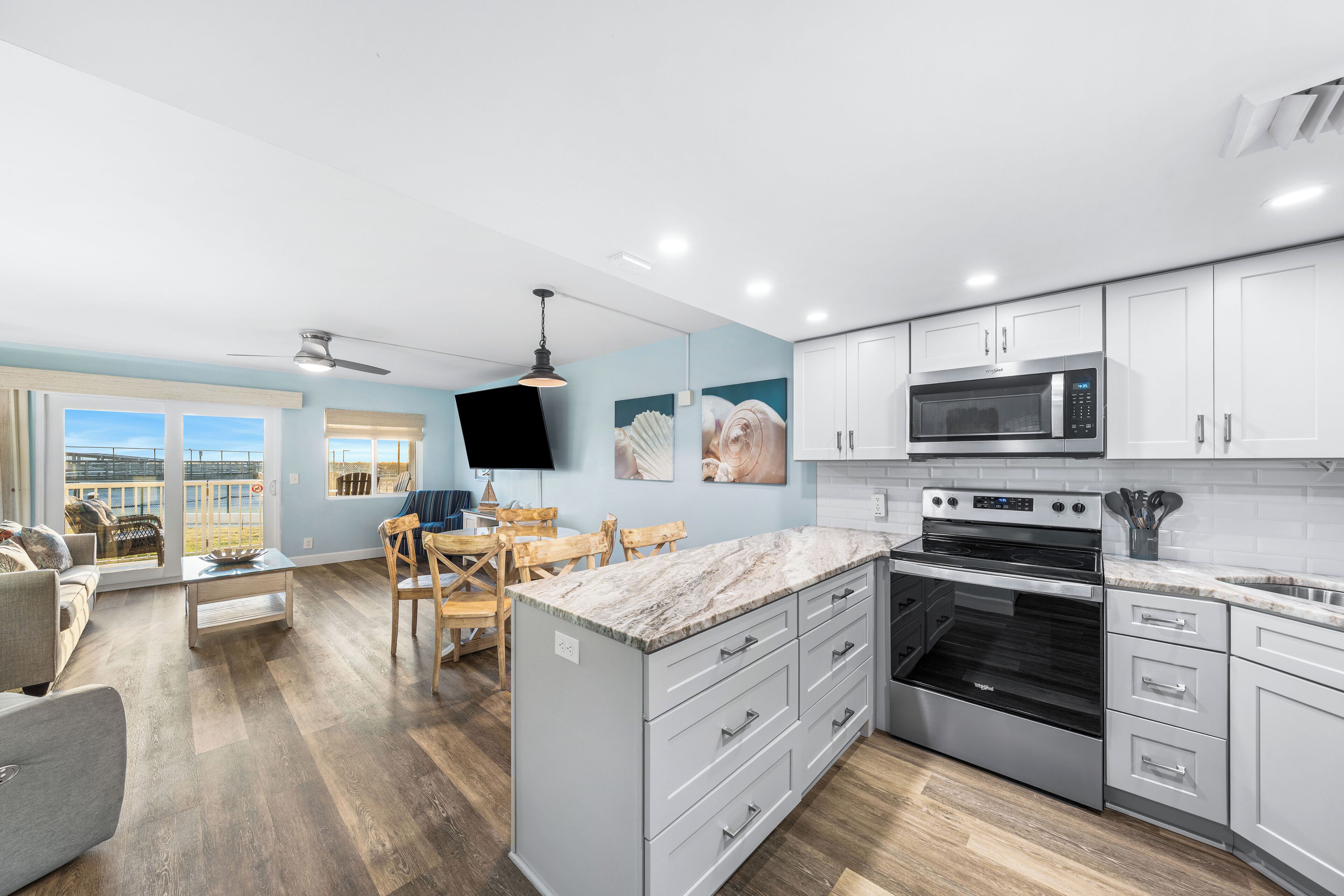 A modern kitchen with white cabinets, a large island, and a built-in microwave.