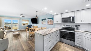 A modern kitchen with white cabinets, a large island, and a built-in microwave. - 117- Beach Level Delight, Walk out to the Beach or Pool, Free Beach Service (Destin)