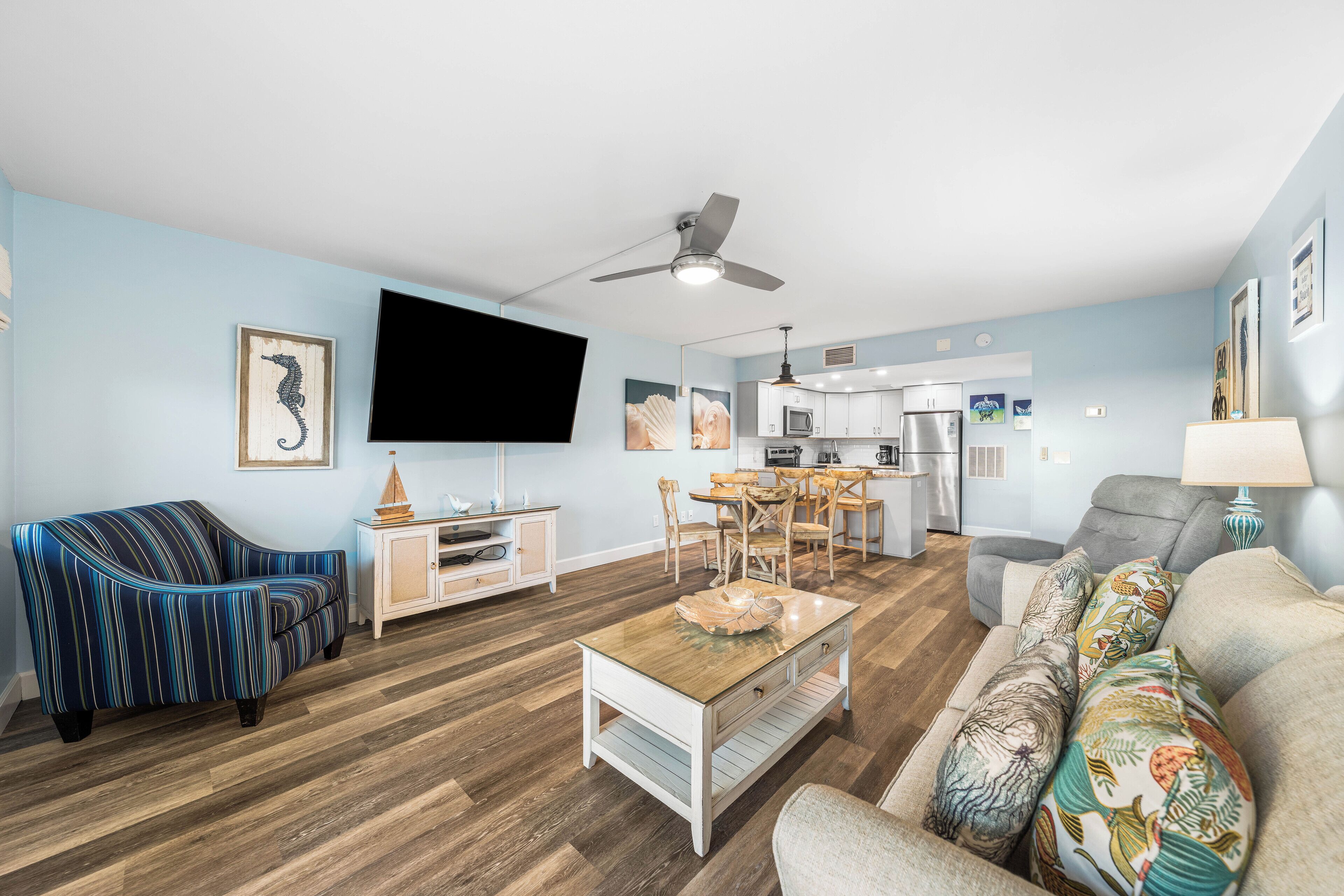 A living room with a sofa, a coffee table, a TV, and a dining area with chairs and a table.