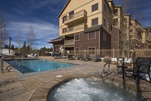 Relax by the rectangular pool surrounded by a deck with lounge chairs and a hot tub.