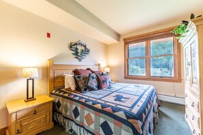 Relax in a spacious bedroom with a large bed, wooden headboard, and a dresser with mirror.