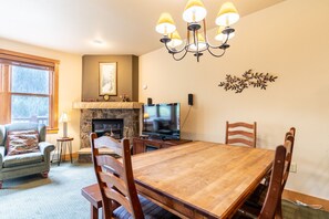 Cozy dining area with a large table, stone fireplace, and a TV.