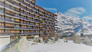 A multi-story hotel with balconies, set against a snowy mountain backdrop. - Studio for 4 in Tignes ski-in/ski-out near shops (Tignes)