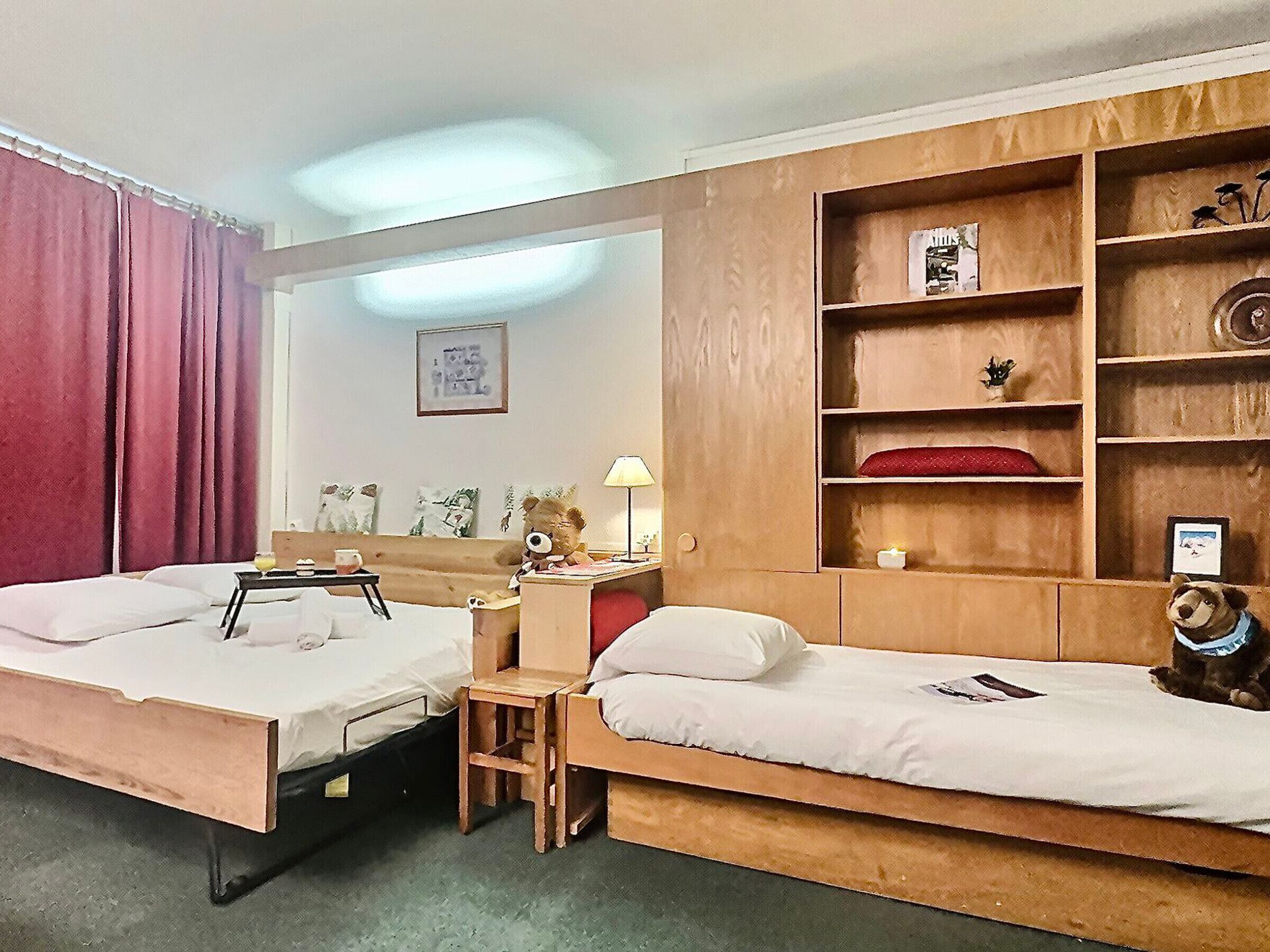 A hotel room with two single beds, a wooden wardrobe, a small table, and a nightstand.