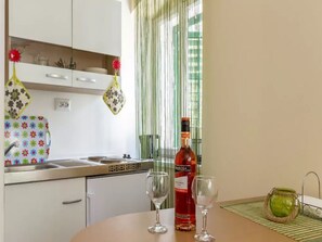 A kitchen with a dining table, a bottle of wine, and two wine glasses.