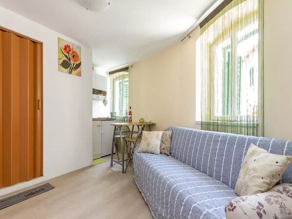 A compact living space with a sofa, a dining table, and a kitchen area.