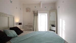 A bedroom with a bed, a chair, a mirror, and a door.