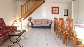 A living room with a wooden staircase, a striped sofa, wooden chairs, and a coffee table.