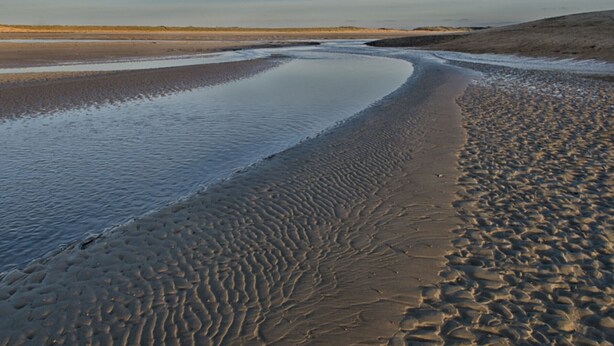A beach with a curved shoreline and a clear sky.