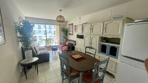 A compact kitchen with a dining table, chairs, and a refrigerator.