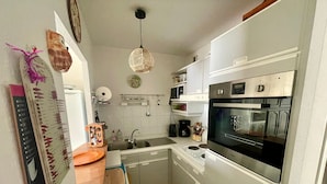 A compact kitchen with white cabinets, a built-in oven, and a hanging light fixture.