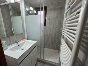 A modern bathroom with a white sink, mirror, and shower enclosure.