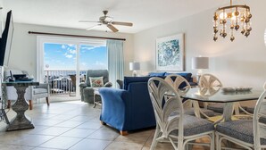 Ein modernes Wohnzimmer mit Balkon, Essbereich und Deckenventilator.