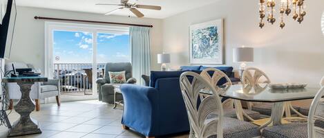 A modern living room with a balcony, a dining area, and a ceiling fan.
